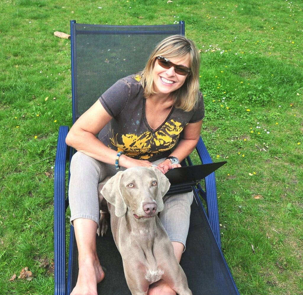 Alice Häuser sitzt mit Maya im Liegestuhl, daneben liegt ein Laptop.